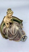 Full view of figurine seated on chair holding bird