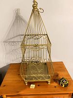 Full view of gold metal decorative cage on table with tape measure for scale