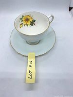 Teacup on saucer showing exterior pale blue, interior flower motif, gold trim