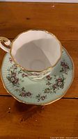 Teacup on saucer showing interior white and exterior mint green floral pattern