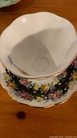 Teacup interior and saucer showing scalloped gold rim and interior crest
