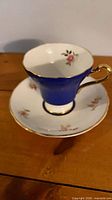 Teacup on saucer showing cobalt exterior, floral interior, gold trim