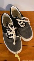 Pair of black/gray Vans low-top sneakers with white laces and soles displayed side by side