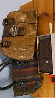 Overview showing all three bags: croc-embossed clutch, striped fabric bag, monogram wallet