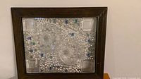 Front view of pressed decorative glass panel with blue accents inside dark brown wood frame