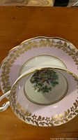 Top view of teacup on saucer showing pink ground and gold leaf border