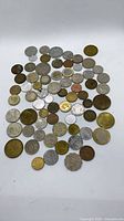 scattered view of over 60 mixed world coins showing varied sizes, metals and wear