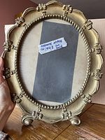 Front view of gold Syroco oval frame showing floral decoration and opening