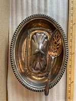Overall view of oval dish, butter liner and server with ruler for scale