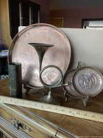 All five items: large copper tray, two small copper plates, brass cylinder vase, brass ring candle holder