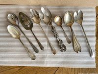 Eight assorted silver-plated utensils laid out