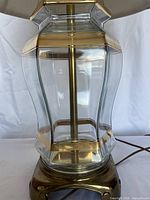 Close-up of clear glass body and brass base of table lamp