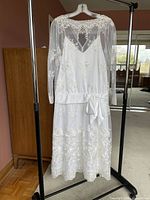 Full view of ivory lace tea-length wedding dress on hanger