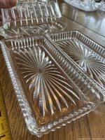 Butter dish with lid removed alongside two matching trays displaying starburst pattern and ribbed borders