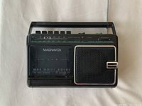 Front view showing Magnavox branding, cassette door, speaker grille, tuning scale and antenna