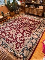 Full view of red, cream, blue wool area rug on floor