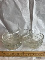 Stack of six clear pressed glass bowls beside ruler showing size