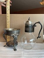 Carafe, lid and ornate stand with ruler showing height