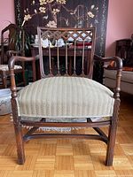 Front view of dark brown wooden armchair with green striped seat