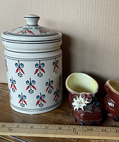 Pair of ceramic boots beside ruler and background object