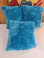 Front view of three turquoise shag pillows