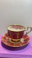 Side view of Paragon teacup on matching saucer showing burgundy colour and gold gilt