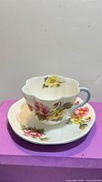 Teacup on saucer showing floral pattern and blue handle