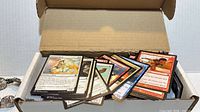 Open box showing assorted Magic: The Gathering cards fanned at front
