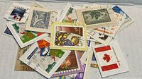 Pile of assorted used postage stamps showing various Canadian and some international designs and denominations