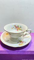Teacup on saucer showing floral design and gold rim