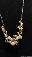 Full view of necklace on display form showing chain and clustered beads