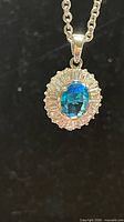 Full view of pendant on chain showing blue crystal and halo setting