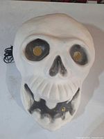 Front view of white plastic skull with black shading, eye and mouth cut-outs