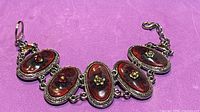 Full view of bracelet showing five red cabochons and clasp