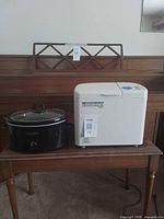 Black Crock-Pot slow cooker and white Toastmaster bread maker displayed on table