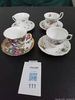 Four bone-china teacup and saucer sets in assorted floral patterns