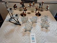 Group shot showing all candle holders: two brass candelabra, metal/glass votive holder, seven glass star tealight holders