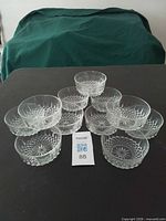 Twelve clear glass dessert bowls arranged on table