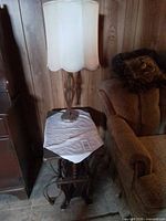 Wood magazine-rack end table beside sofa with lamp having cream drum shade