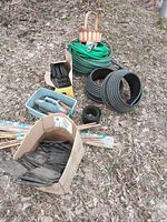 Group view of hose, drainage tubing, edging pieces, stakes and tote of hand tools