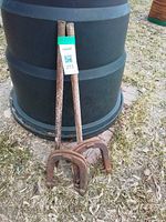 Two rusted steel stakes with four horseshoes at base leaning against barrel