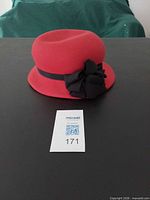 Front view of red felt cloche hat showing shape, color, ribbon and bow