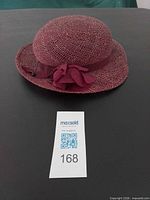 Top and front view of red straw hat with ribbon and flower detailing