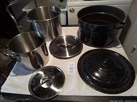 Three pots with lids displayed: enamel canner, two stainless stock pots