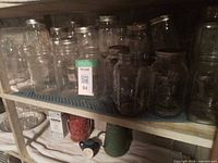 Shelf with multiple clear glass Mason jars various sizes, most lidless