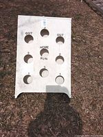 Front view of white baseball-style beanbag toss board showing nine holes and printed score labels