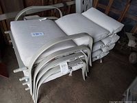 Stacked light gray metal patio chairs with off-white cushions