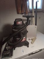 Canister vacuum with hose, accessory holder and various attachments on white surface