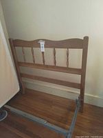 Hardwood spindle headboard with partial metal frame on wooden floor