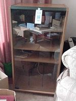 Front view of wood stereo cabinet with glass door and interior shelves